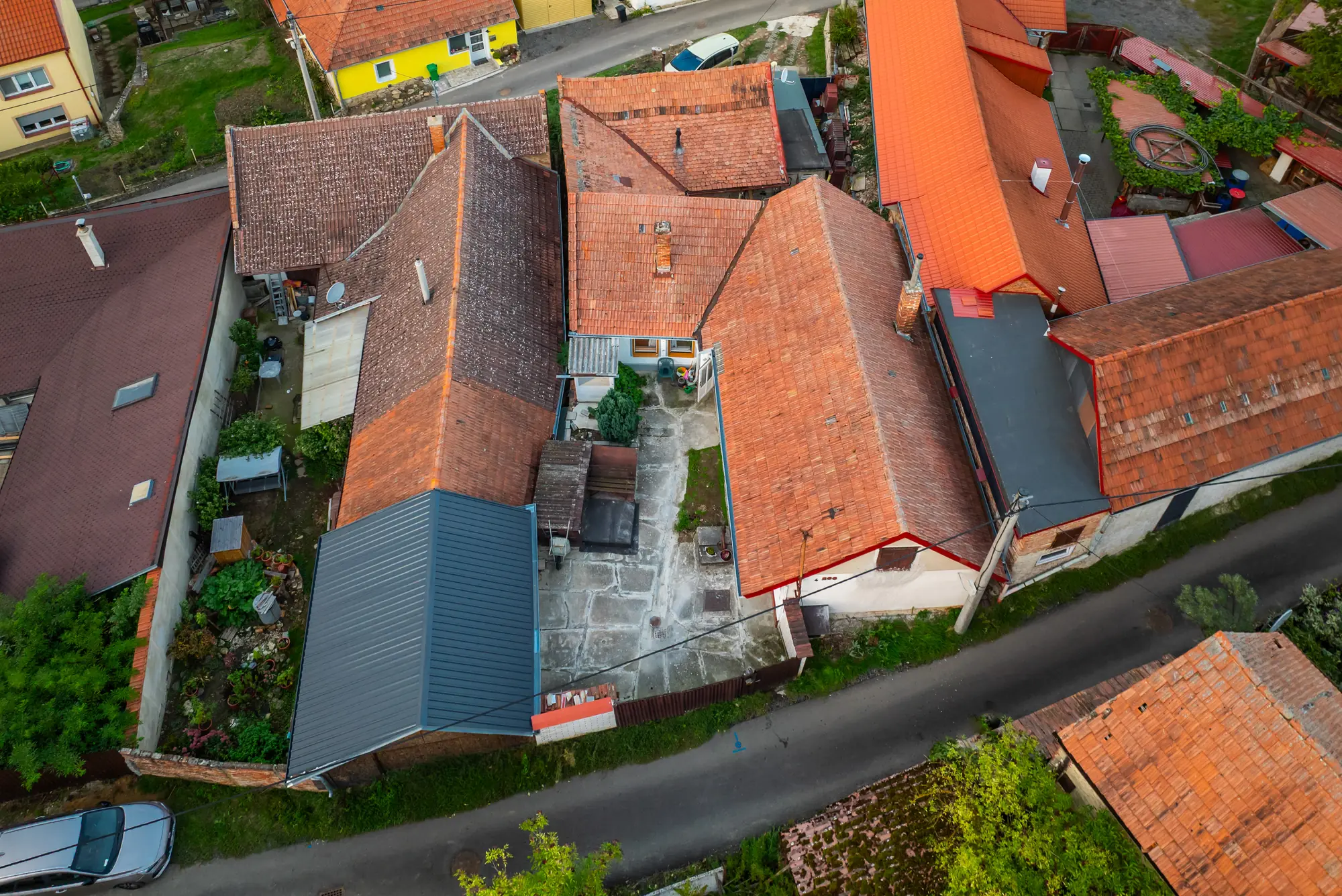 Chalupa a dvůr z dronu mezi okolními střechami